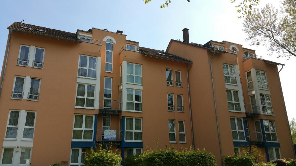 un bâtiment orange avec des fenêtres blanches et un arbre dans l'établissement Apartmentcenter Koblenz, à Coblence