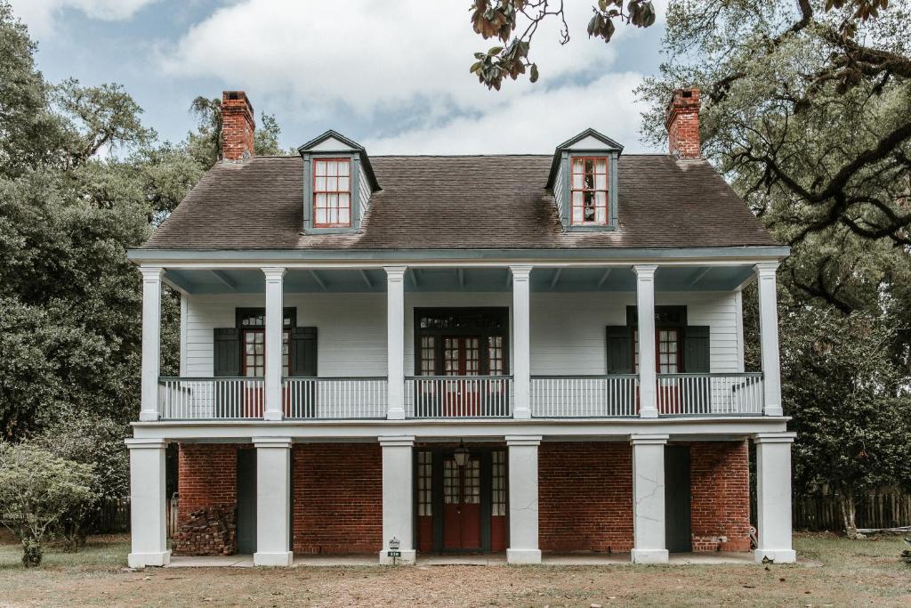 ein altes Backsteinhaus mit weißen Säulen in der Unterkunft Maison Mouton Bed & Breakfast in Lafayette