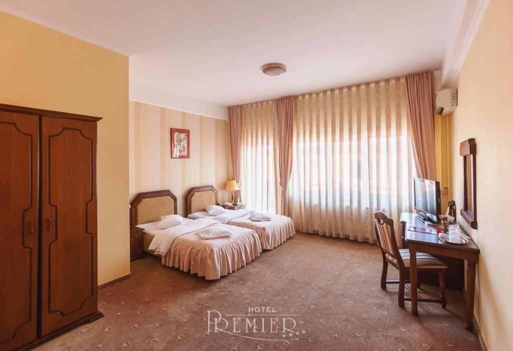 a hotel room with two beds and a desk and a television at Hotel Premier in Cluj-Napoca