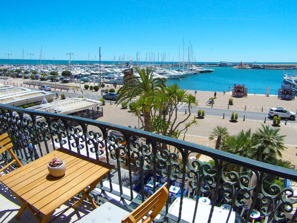 un balcone con tavolo, sedie e un porto turistico. di La Torre Oceanside a Cambrils