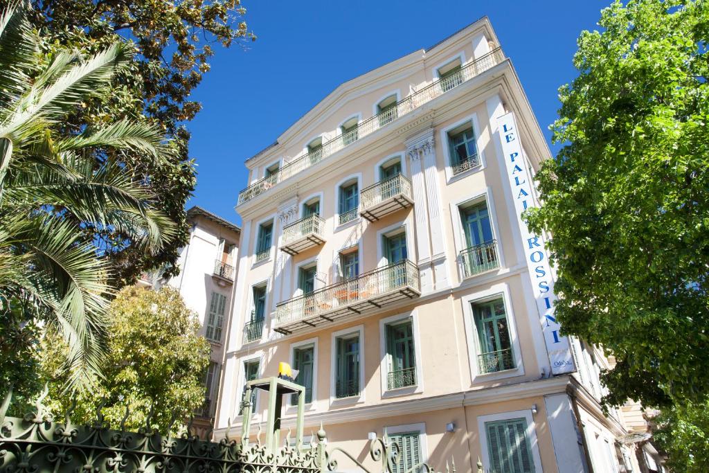 un grande edificio bianco con alberi di fronte di Odalys City Nice Le Palais Rossini a Nizza