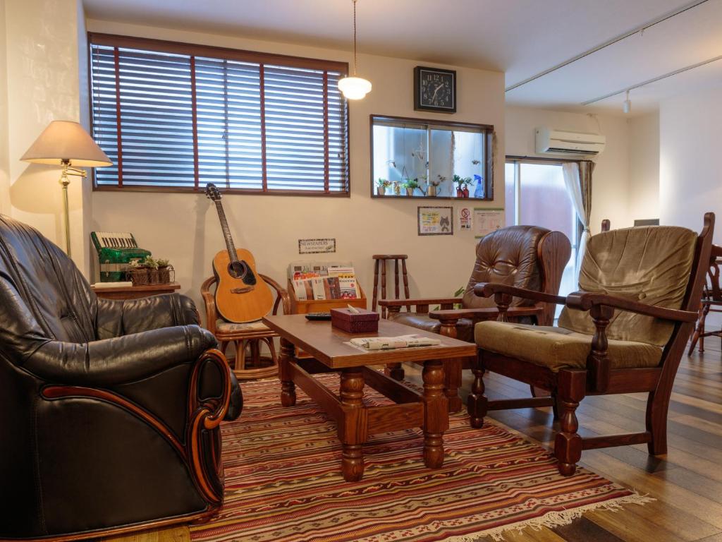 un soggiorno arredato con una chitarra di J-Hoppers Hiroshima Guesthouse a Hiroshima