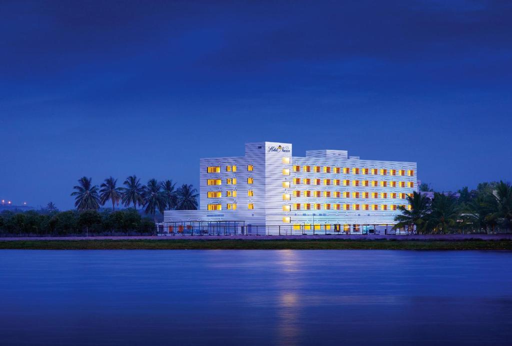 un grand bâtiment avec des lumières en face de l'eau dans l'établissement Hotel Naveen Lakeside, à Hubli