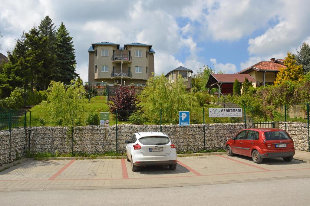 zwei Autos auf einem Parkplatz vor einem Gebäude geparkt in der Unterkunft Apartments Vila Vrdnik in Vrdnik