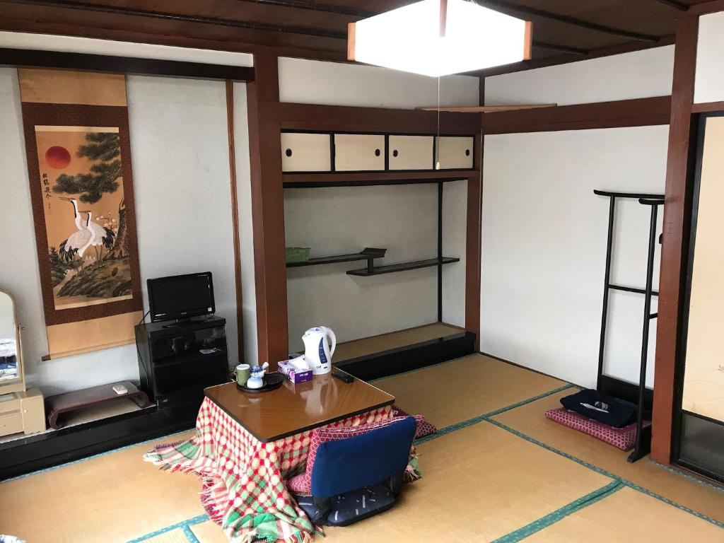 een woonkamer met een tafel en een televisie bij Niko Ryokan in Aizuwakamatsu