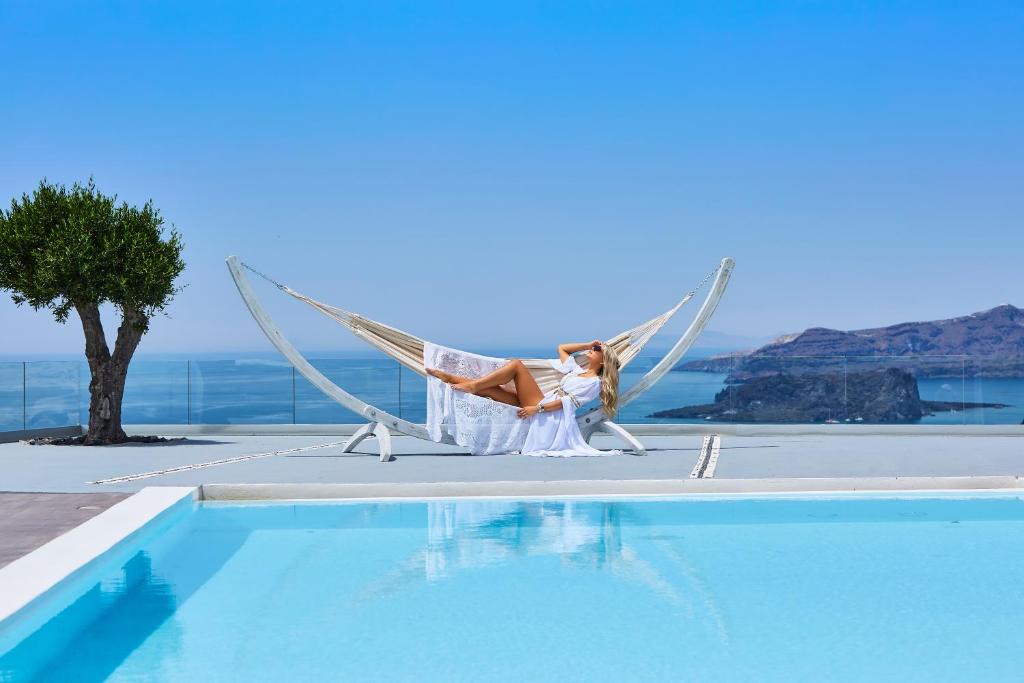 una mujer sentada en una hamaca junto a una piscina en Thermes Luxury Villas And Spa, en Megalokori