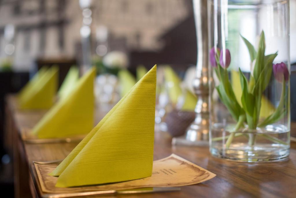 a table with yellow napkins and a vase with flowers at Leipziger Hof in Fulda