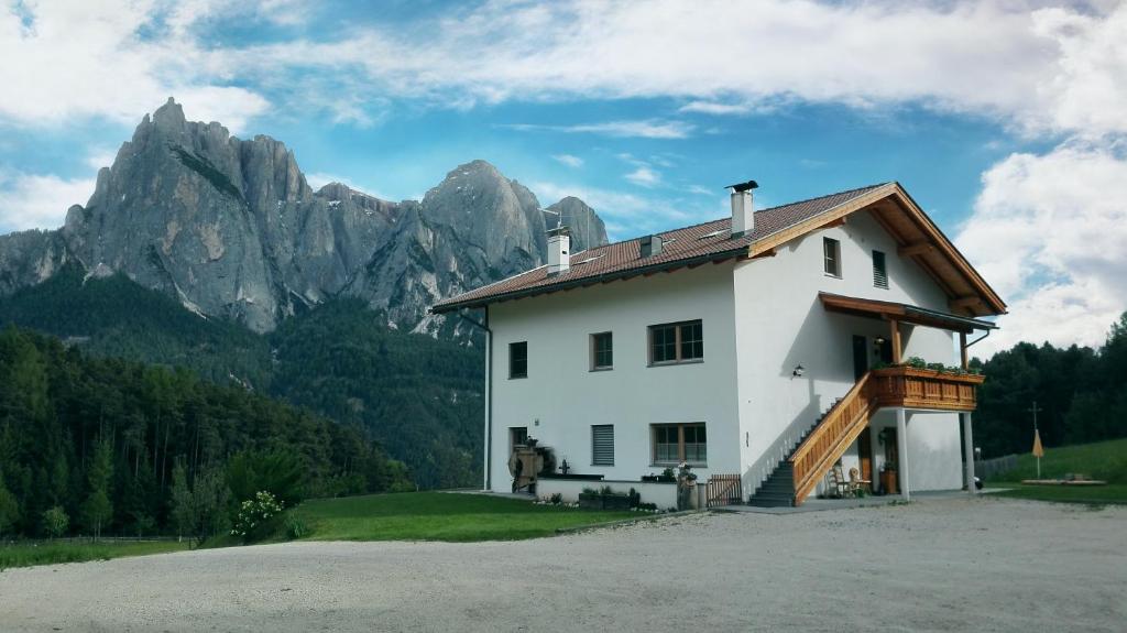 una casa bianca con montagne sullo sfondo di Parlunkhof a Castelrotto