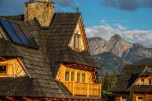 una baita di tronchi con tetto e montagne sullo sfondo di Willa Giewontka a Witów