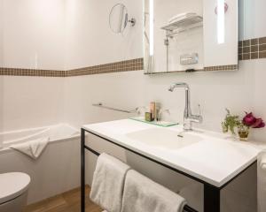 uma casa de banho branca com um lavatório e um WC em Hotel Malte - Astotel em Paris