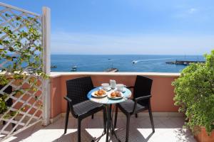 een tafel en stoelen op een balkon met uitzicht op de oceaan bij Vista d'Amalfi in Amalfi