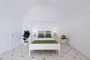 een witte slaapkamer met een wit bed met groene lakens bij Vista d'Amalfi in Amalfi