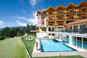 a large building with a swimming pool in front of it at Hotel Chalet Tianes - Alpine Relax in Castelrotto