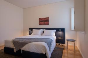 um quarto com uma cama grande e lençóis brancos em Oporto Serviced Apartments - Alvares Cabral no Porto