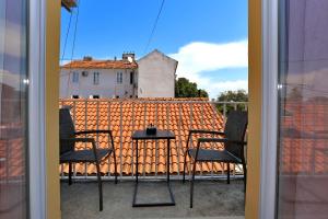 a table and chairs on a balcony with an orange roof at Shabby chic rooms in Zadar