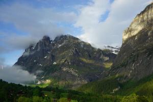 ein Berg mit Wolken und Bäumen davor in der Unterkunft Hotel Alpenblick in Grindelwald