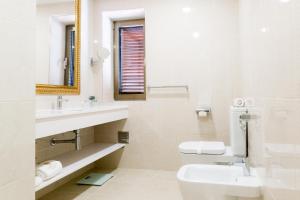 a bathroom with a sink and a toilet and a mirror at Hotel Lis Batalha in Batalha