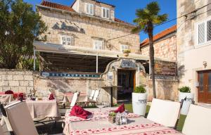 ein Restaurant mit Tischen und Stühlen vor einem Gebäude in der Unterkunft Guesthouse Mimbelli in Orebić