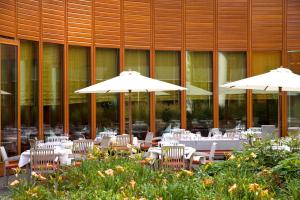 deux tables et chaises avec parasols devant un bâtiment dans l'établissement Steigenberger Airport Hotel Amsterdam, à Schiphol