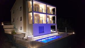 トロギールにあるLuxury Villa Star Lights Trogir - heated pool, hot tub, gym, billiardの夜の青いプール付きの家