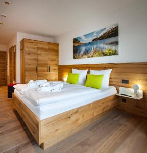 una camera da letto con un grande letto in legno con cuscini verdi di Das Heimsitz a Brixen im Thale