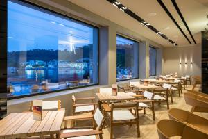 un restaurante con mesas y sillas y una gran ventana en Angelica Hotel, en Limenas