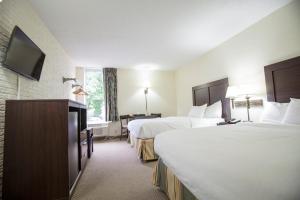 a hotel room with two beds and a flat screen tv at Inns of Virginia Arlington in Arlington