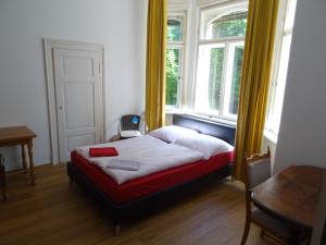 uma cama num quarto com duas janelas e uma mesa em Villa Bellevue Dresden em Dresden