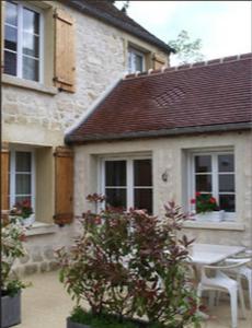 a house with a table and chairs in front of it at Gîte Les Rainettes in Coye-la-Forêt