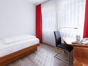 um quarto com uma cama, uma secretária e uma cadeira em DORMERO Hotel Dresden Airport em Dresden