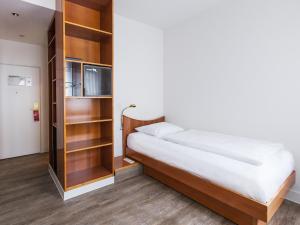 um quarto com uma cama e uma estante de livros em DORMERO Hotel Dresden Airport em Dresden