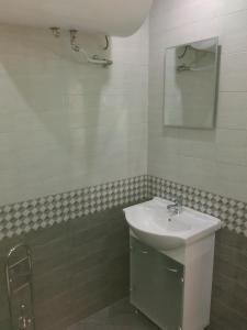 La salle de bains blanche est pourvue d'un lavabo et d'un miroir. dans l'établissement Apartments Hristovi, à Sandanski