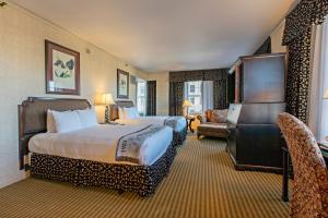 um grande quarto de hotel com duas camas e uma cadeira em The Brown Hotel em Louisville