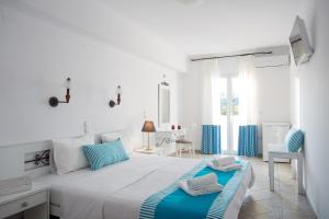 - une chambre blanche avec un grand lit aux accents bleus dans l'établissement Iris Beach Hotel, à Monemvasia