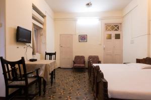 um quarto com duas camas e uma mesa e cadeiras em Bed and Breakfast at Colaba em Mumbai