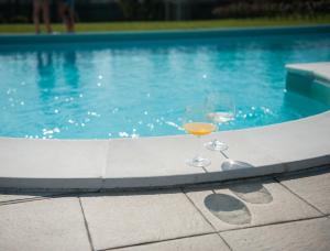 two glasses of wine sitting next to a swimming pool at Residence Cà Beregana in Vicenza