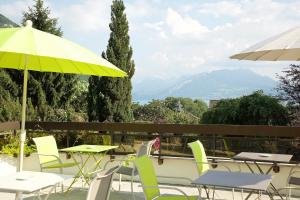 eine Terrasse mit Tischen, Stühlen und einem Sonnenschirm in der Unterkunft Centre Jean XXIII in Annecy