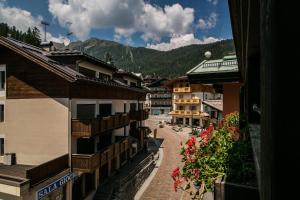 una calle en una ciudad con edificios y flores rojas en Hotel Posta R.T.A., en Madonna di Campiglio