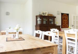 uma sala de jantar com uma mesa de madeira e cadeiras brancas em Villa Viriditas em Elbingerode