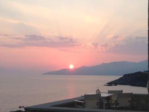 un coucher de soleil sur l'eau avec le soleil dans le ciel dans l'établissement Katikies Manis, à Kardamyli