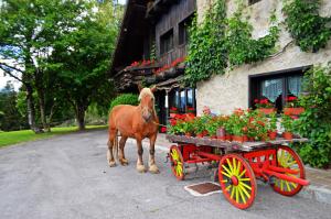 un caballo de pie junto a una carreta roja con flores en Albergo Ristorante Al Fratè da Streza, en Madonna di Campiglio