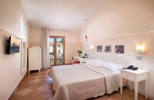 a bedroom with a white bed and a desk and a window at Marin Hotel in Pula