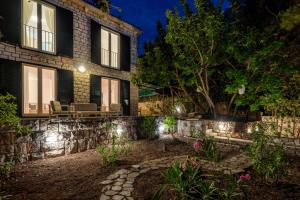 a stone house with lights in the yard at night at Pine Beach Villa in Hvar