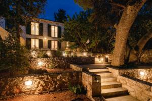 a house with a stone wall and stairs at night at Pine Beach Villa in Hvar