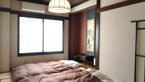 um quarto com uma cama e duas janelas em Guest House Kuranomachi ゲストハウス蔵の街 em Tochigi