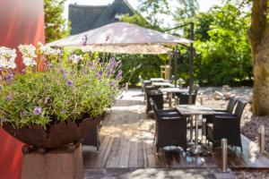 un patio con tavoli, sedie e un vaso di fiori di Das Frühstückshotel Sankt Peter-Ording a Sankt Peter-Ording