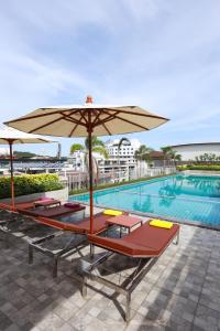 una piscina con diverse sedie a sdraio e ombrellone di The Whisper Hotel a Centro di Pattaya