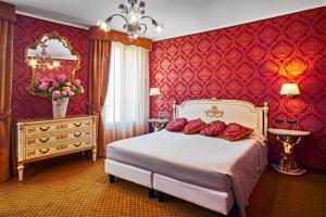 una camera da letto con un letto con pareti rosse e uno specchio di Hotel Gardena a Venezia