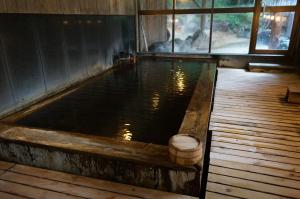 uma piscina de água num quarto com piso de madeira em Kazeya em Takayama