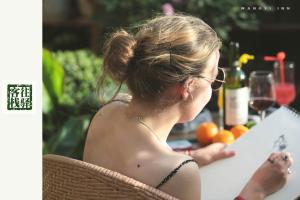 a woman sitting at a table with a glass of wine at Zhangjiajie Wangyi Inn in Zhangjiajie